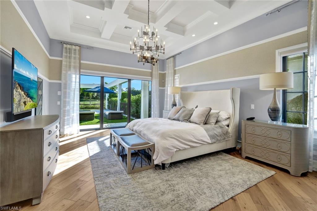 16988 Fairgrove Way Naples, FL 34110 - Photo 13 of 34 a spacious bedroom with a bed and a chandelier