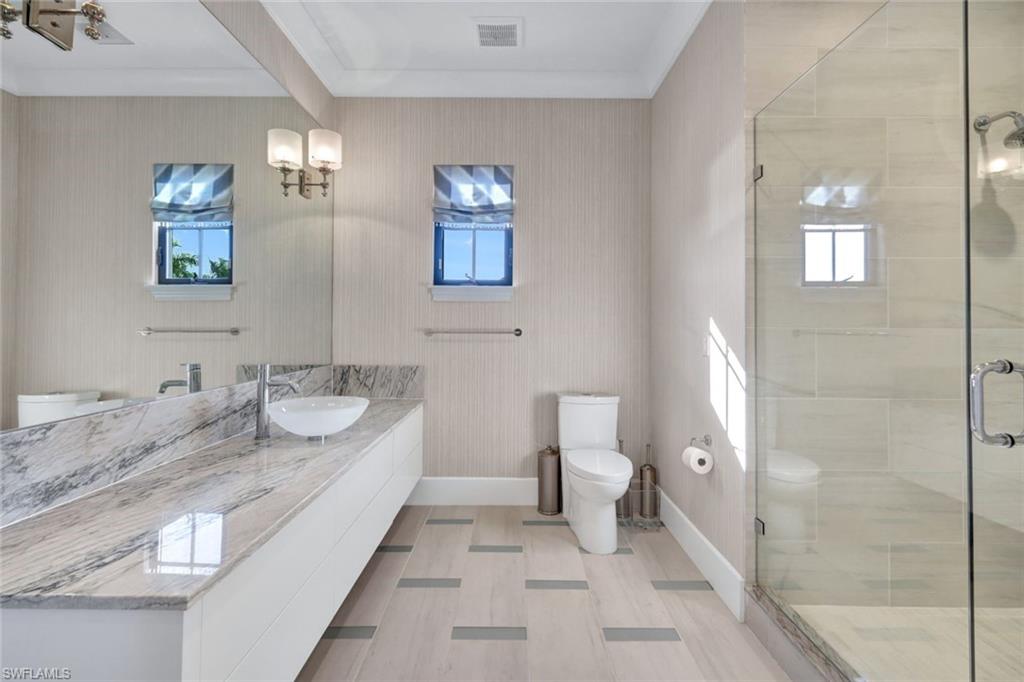 16988 Fairgrove Way Naples, FL 34110 - Photo 20 of 34 a bathroom with a granite countertop sink a toilet and a mirror