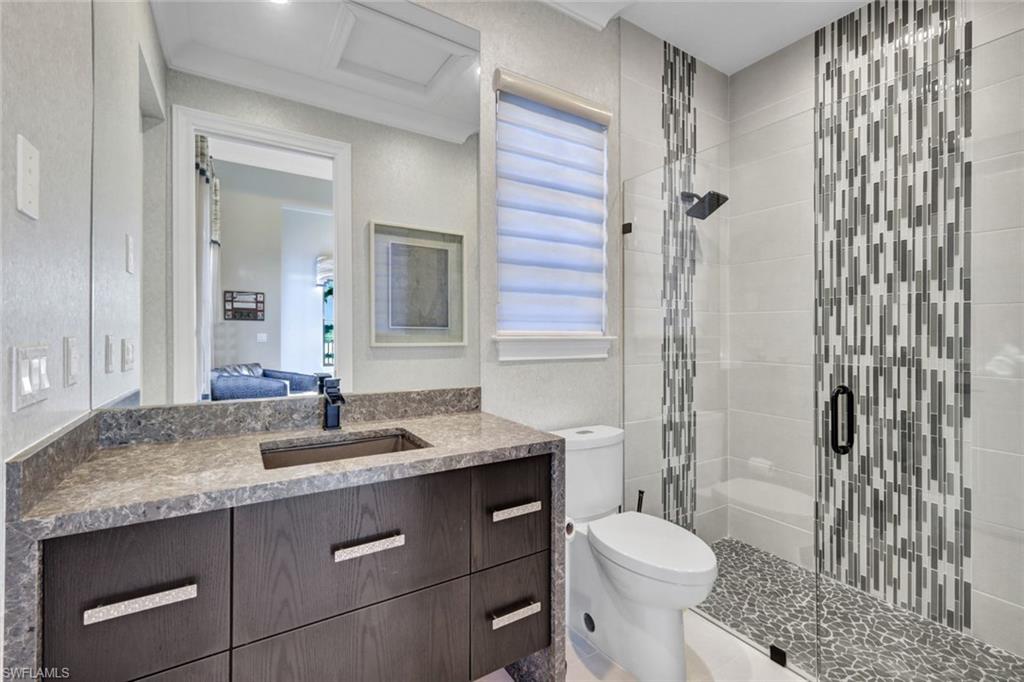 16988 Fairgrove Way Naples, FL 34110 - Photo 24 of 34 a bathroom with a granite countertop sink toilet mirror and shower
