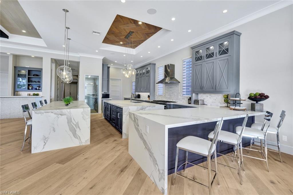 16988 Fairgrove Way Naples, FL 34110 - Photo 10 of 34 a kitchen with stainless steel appliances kitchen island granite countertop a stove a sink a dining table and chairs