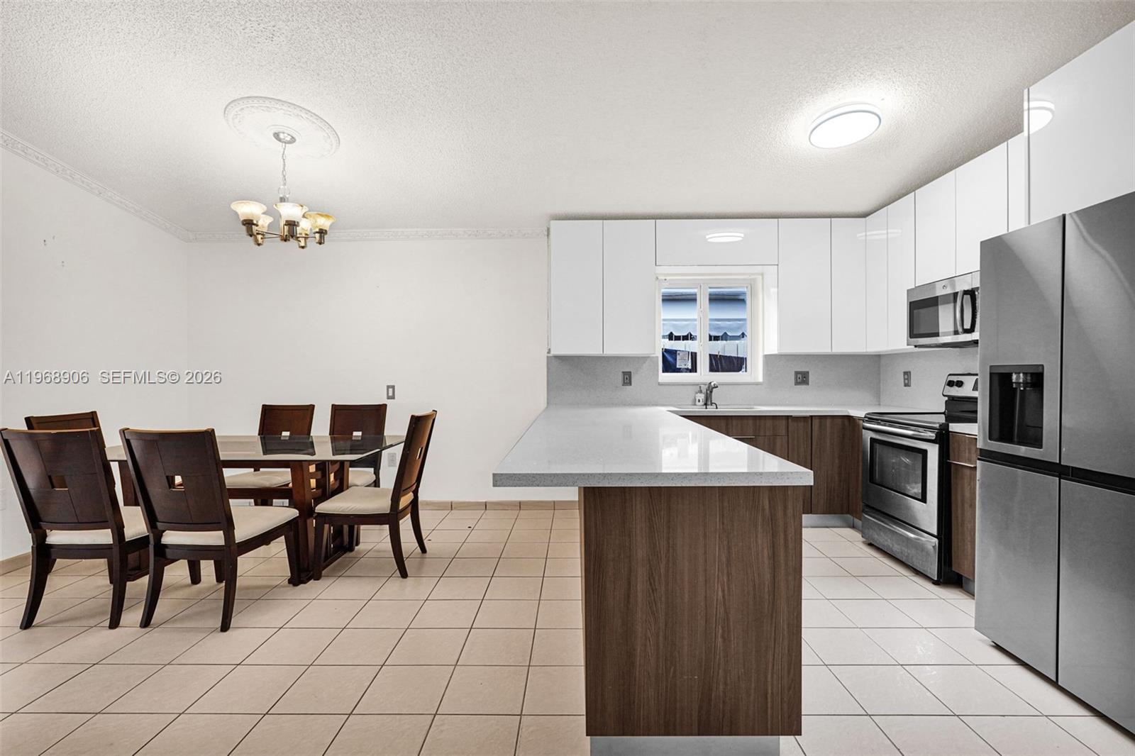 3289 West 70th Street Hialeah, FL 33018 - Photo 13 of 50 a kitchen with stainless steel appliances granite countertop a dining table chairs refrigerator and microwave