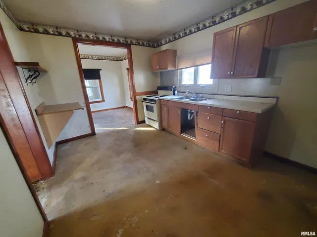 a kitchen with stainless steel appliances granite countertop a sink a stove a refrigerator a washer dryer and white cabinets