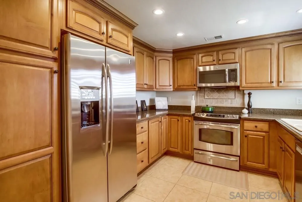 16632 Roca Drive San Diego, CA 92128 - Photo 15 of 44 a kitchen with stainless steel appliances granite countertop a refrigerator a stove and a sink with wooden floor