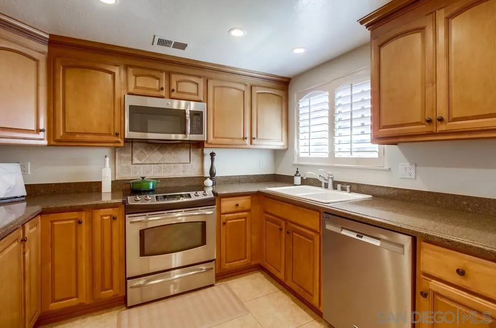 16632 Roca Drive San Diego, CA 92128 - Photo 16 of 44 a kitchen with stainless steel appliances granite countertop a sink stove and microwave