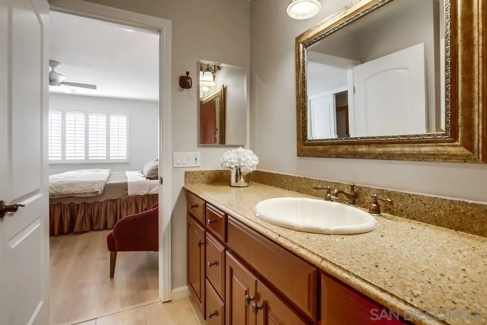 16632 Roca Drive San Diego, CA 92128 - Photo 24 of 44 a bathroom with a granite countertop sink a mirror and a bathtub