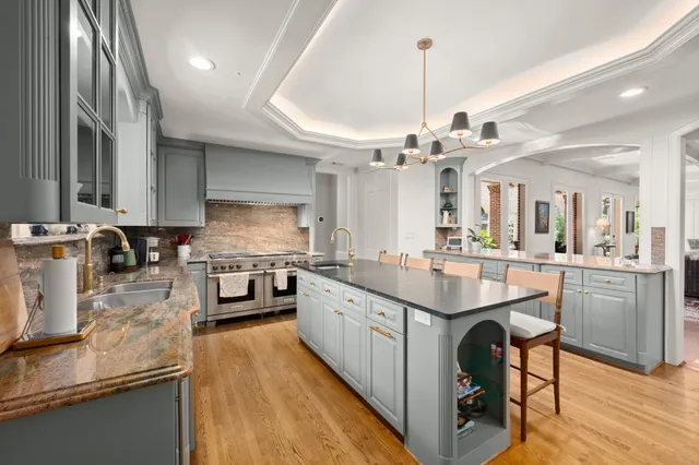 a kitchen with kitchen island granite countertop a sink appliances and cabinets