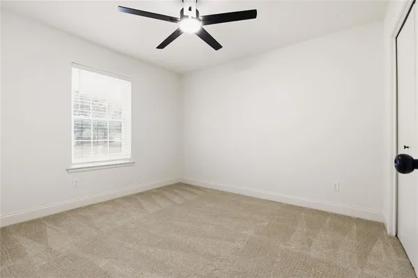 an empty room with a window and a fan