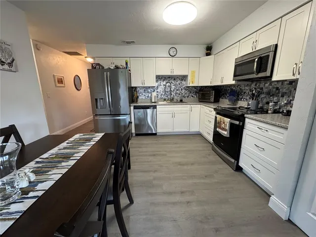 a kitchen with granite countertop white cabinets and stainless steel appliances