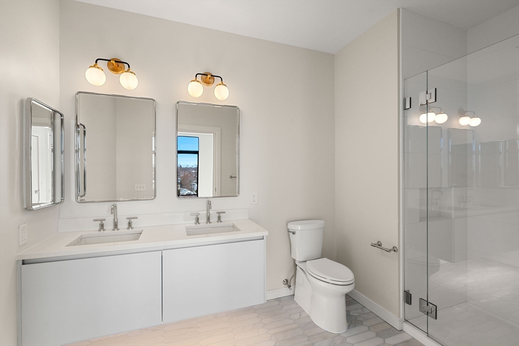 191 Washington Street, Unit 710 Boston, MA 02135 - Photo 17 of 35 a bathroom with a toilet sink vanity and mirror