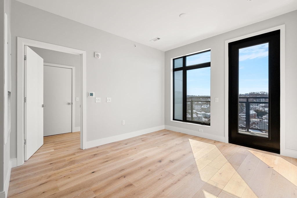 191 Washington Street, Unit 710 Boston, MA 02135 - Photo 4 of 35 a view of an empty room with window and wooden floor