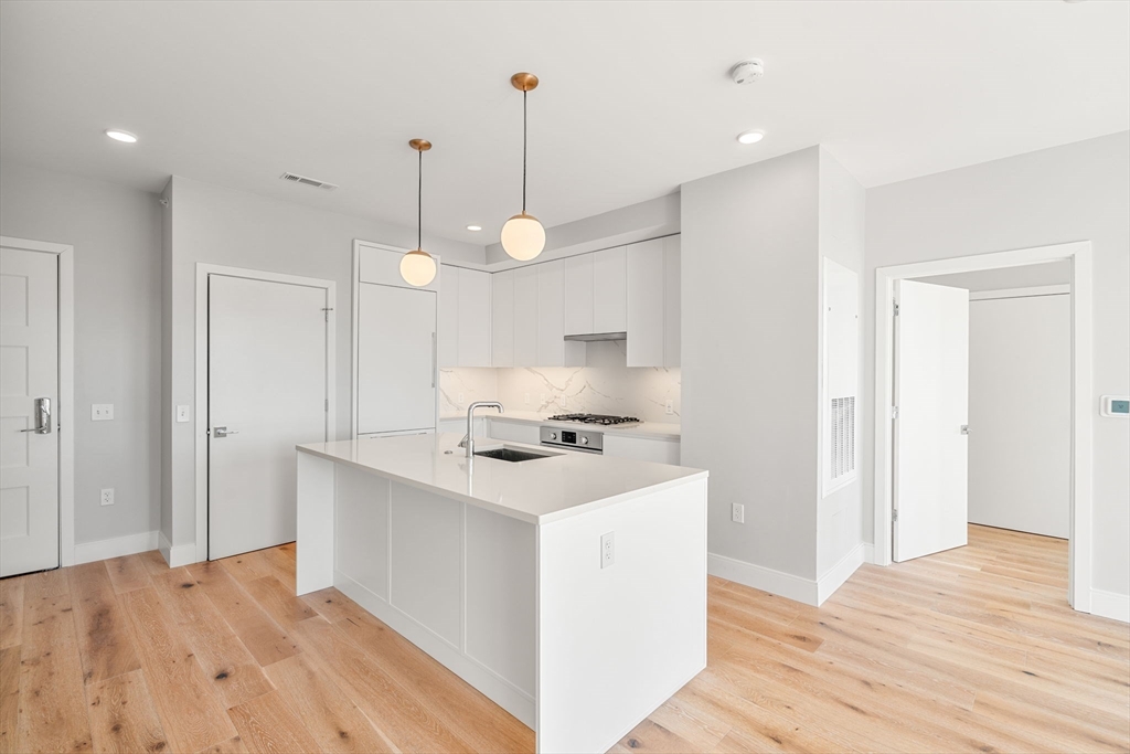 191 Washington Street, Unit 710 Boston, MA 02135 - Photo 7 of 35 a kitchen with kitchen island a sink stainless steel appliances and wooden floor