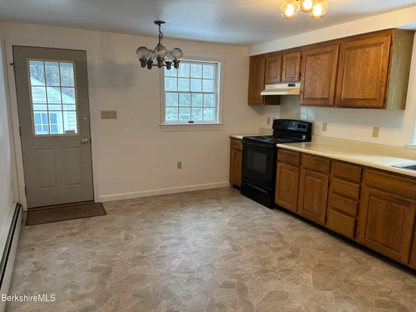 an empty room with wooden floor chandelier and windows