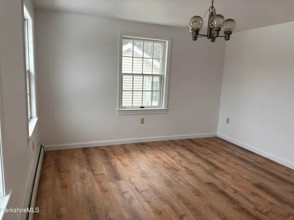 a view of an empty room with wooden floor and fan