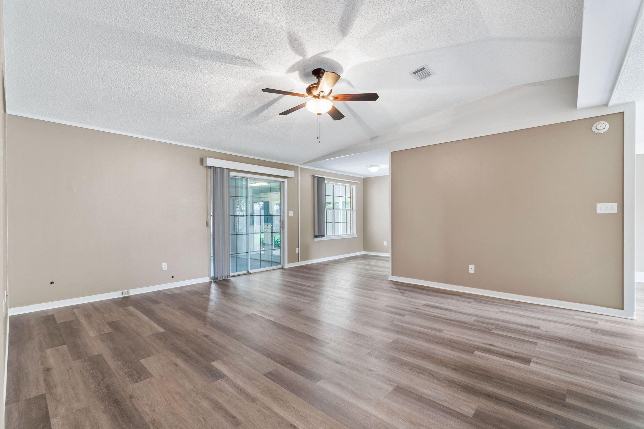 2760 Augustus Road Navarre, FL 32566 - Photo 8 of 40 an empty room with wooden floor ceiling fan and windows