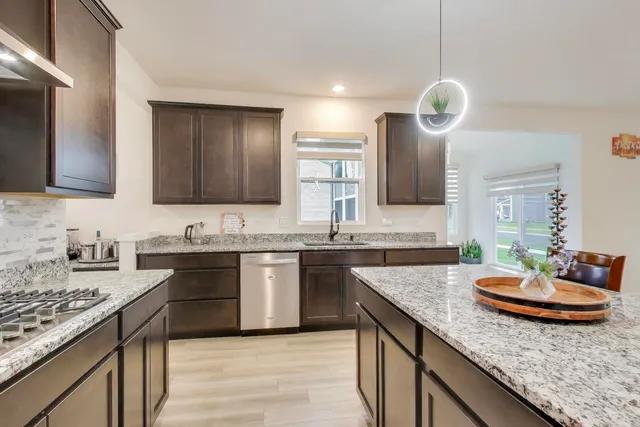 a kitchen with granite countertop kitchen island stainless steel appliances a sink stove and cabinets