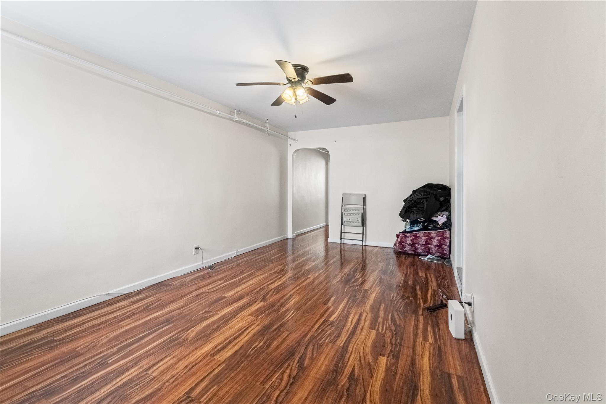 203-10 Murdock Avenue Queens, NY 11412 - Photo 4 of 18 Unfurnished room with arched walkways, dark wood finished floors, and ceiling fan