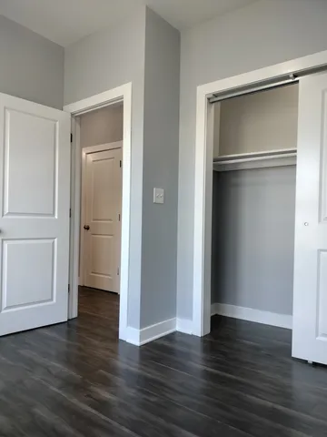 a view of an empty room with wooden floor & closet