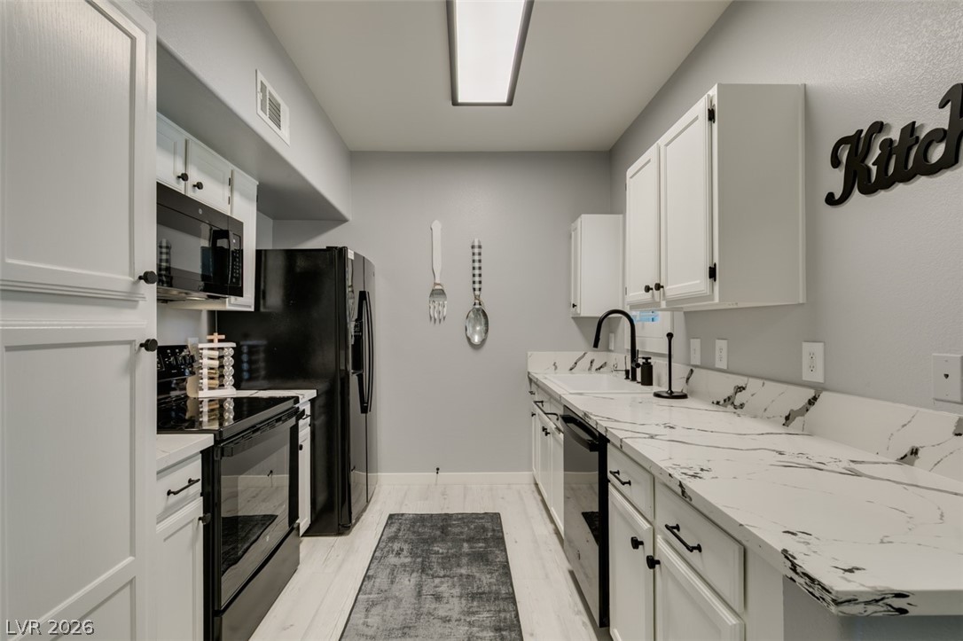 7255 West Sunset Road, Unit 1103 Las Vegas, NV 89113 - Photo 27 of 35 White cabinetry, black appliances, and marbled countertops define this efficient culinary space.