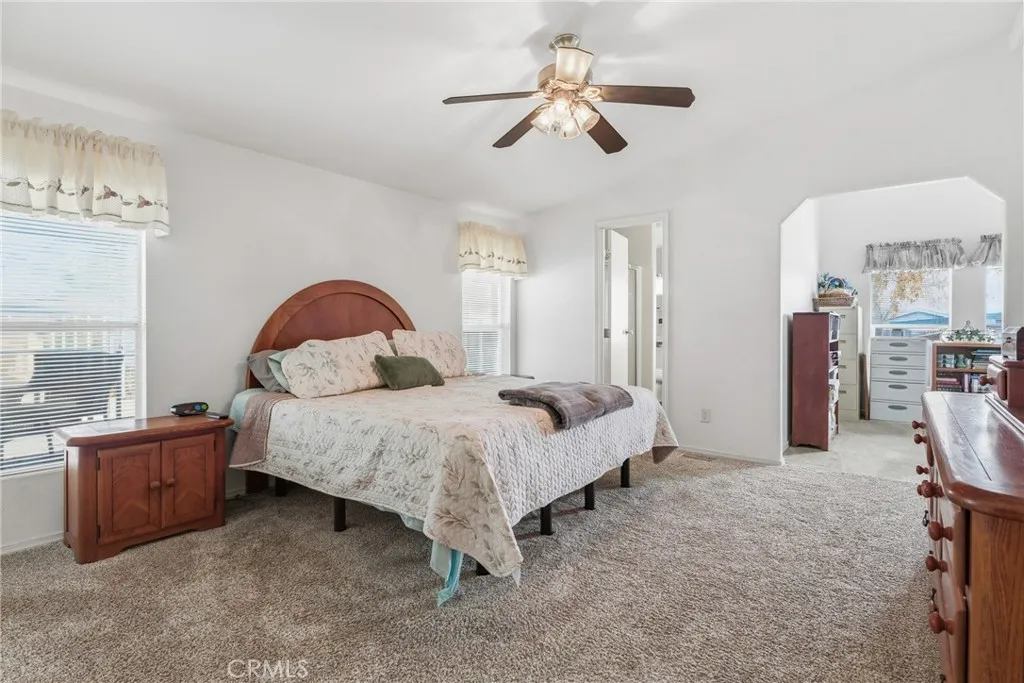 20843 Waalew Road, Unit C48 Apple Valley, CA 92307 - Photo 17 of 33 a spacious bedroom with a bed a window and a chandelier