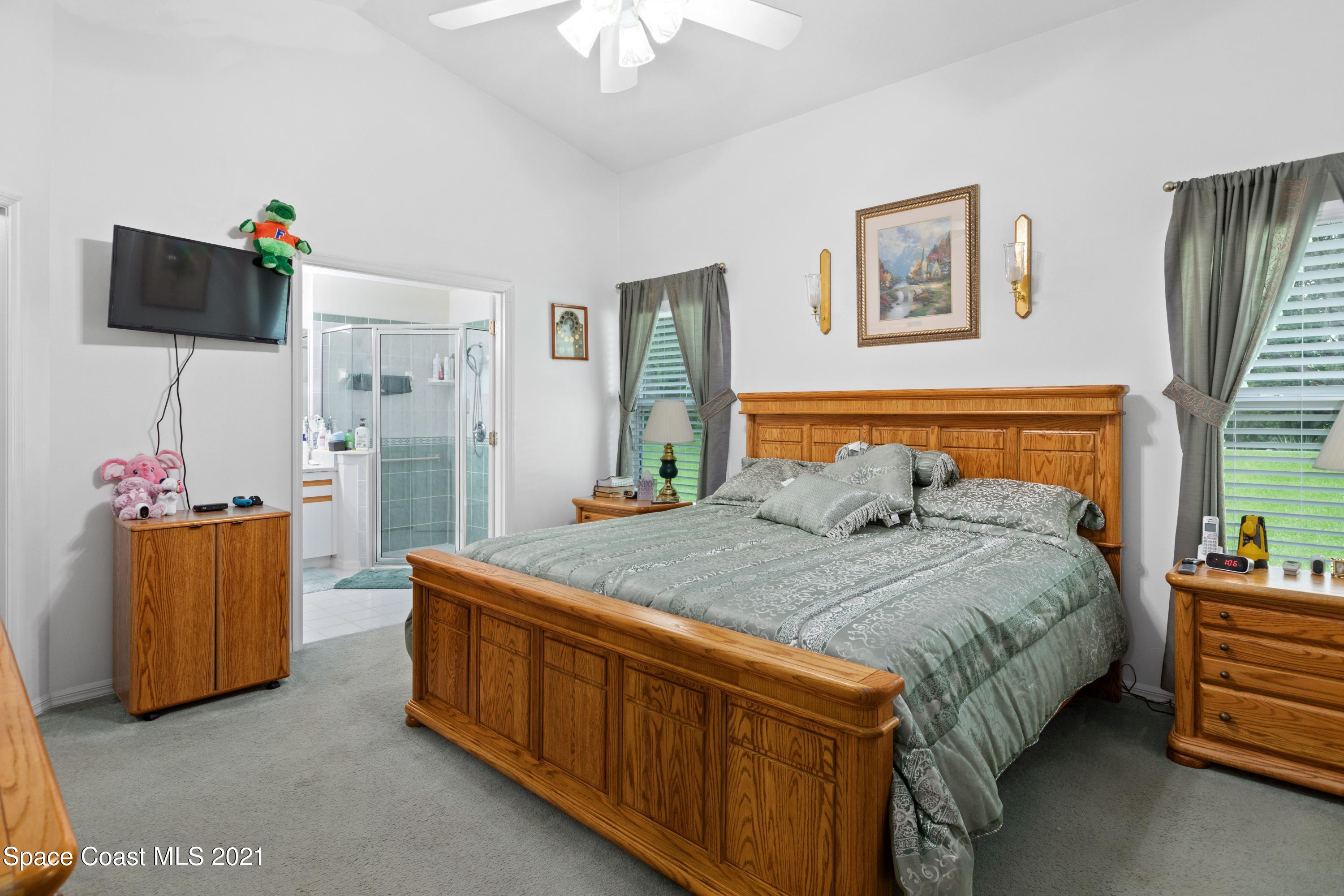 1120 Meadowbrook Road Northeast Palm Bay, FL 32905 - Photo 17 of 33 a bedroom with a bed and a flat tv screen on dresser