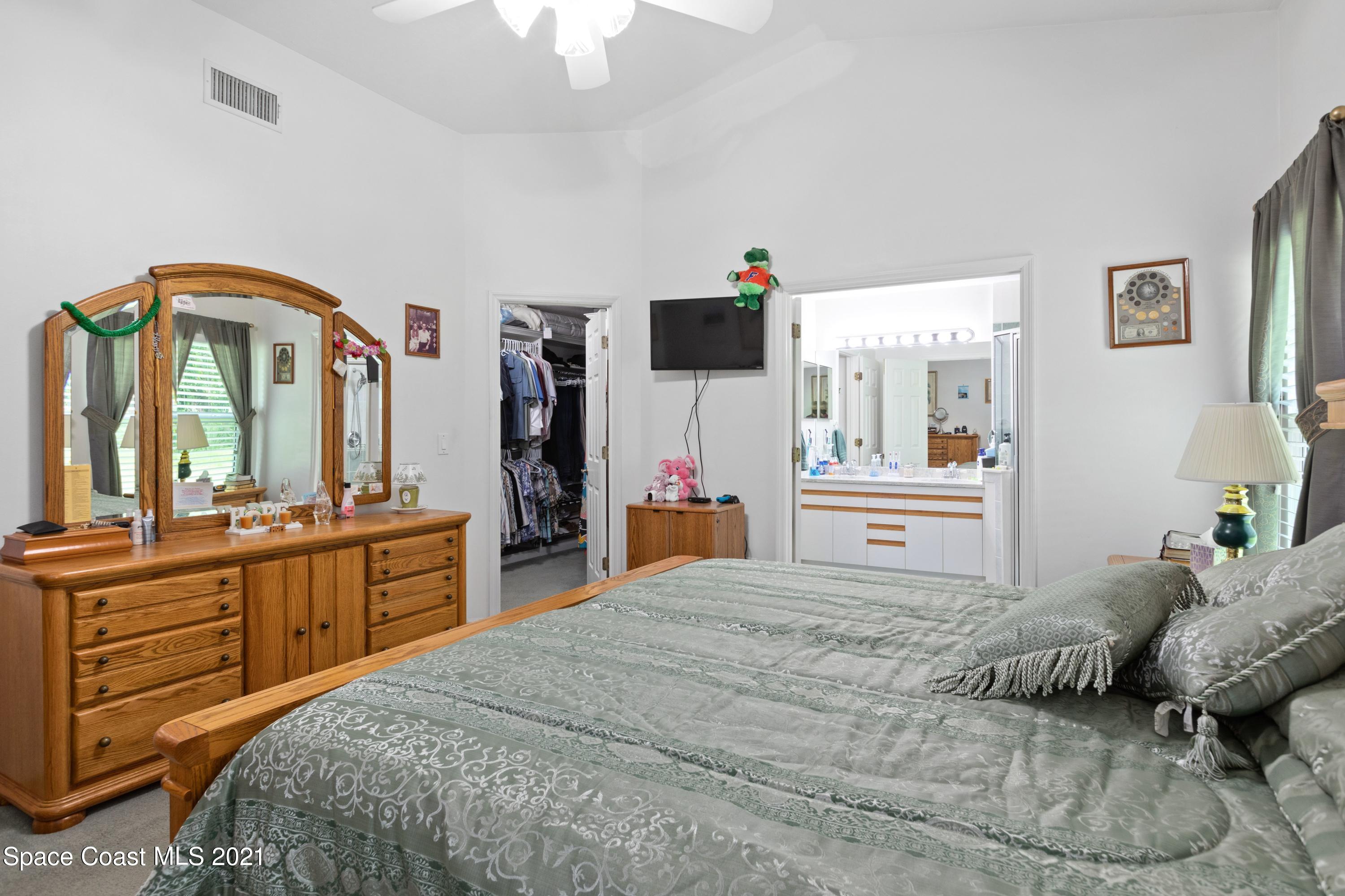 1120 Meadowbrook Road Northeast Palm Bay, FL 32905 - Photo 18 of 33 a bedroom with a large bed and a chandelier
