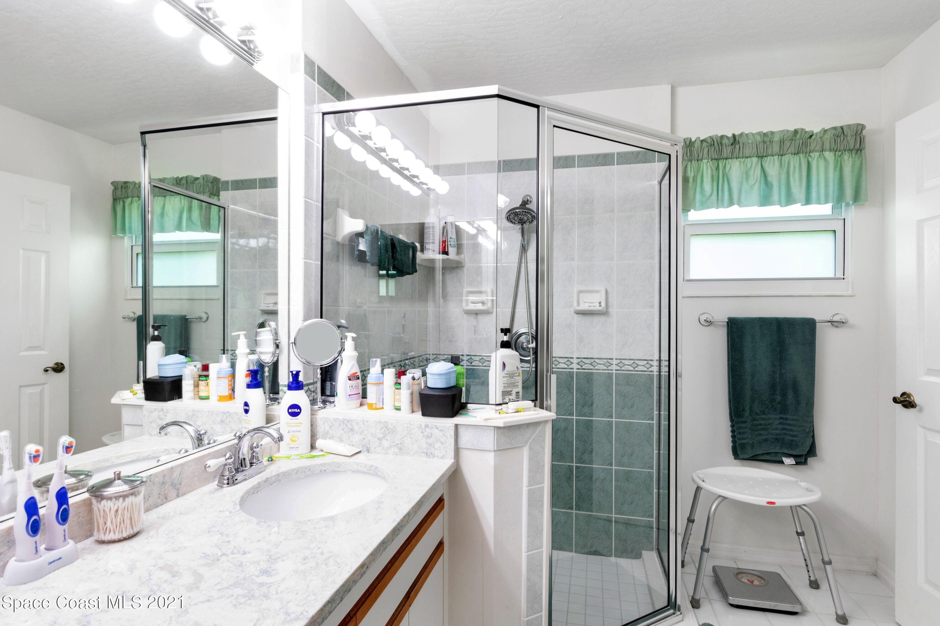 1120 Meadowbrook Road Northeast Palm Bay, FL 32905 - Photo 19 of 33 a bathroom with a granite countertop sink a toilet a mirror and shower