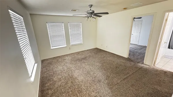 an empty room with windows and fan