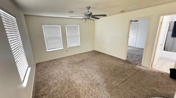 an empty room with windows and a ceiling fan
