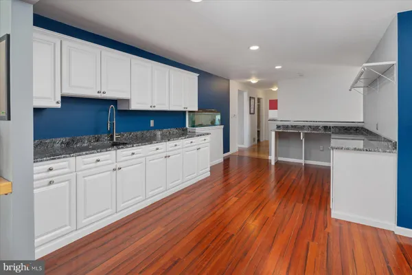 an empty room with wooden floor chandelier fan and windows