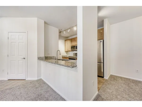 a kitchen with kitchen island granite countertop a sink refrigerator and cabinets