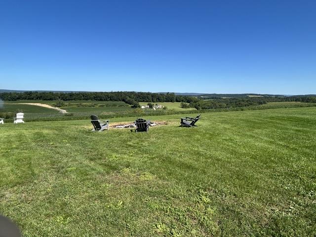 9191 Red Road Kempton, PA 19529 - Photo 21 of 25 Rolling green hills and distant woodlands stretch beneath an expansive blue sky.