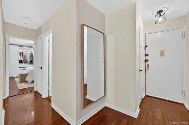 a view of a hallway with wooden floor and a bathroom