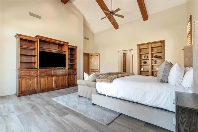 a spacious bedroom with a large bed a chandelier and windows