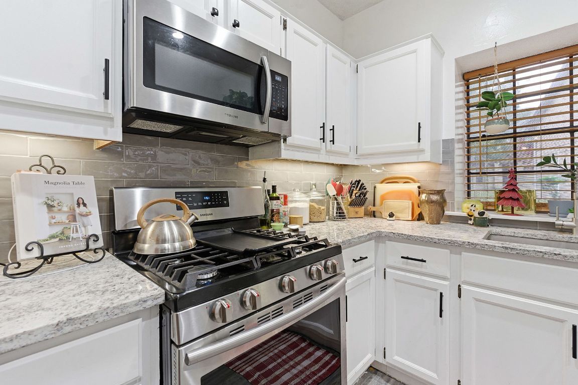 10819 Crown Colony Drive, Unit 33 Austin, TX 78747 - Photo 13 of 27 a kitchen with stainless steel appliances granite countertop a stove and a microwave