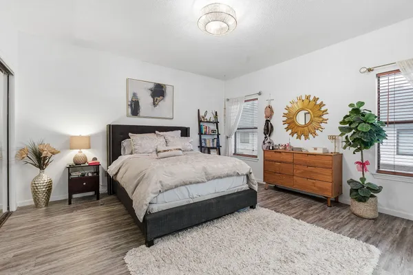 a bedroom with a bed potted plant on dresser and a wooden floor