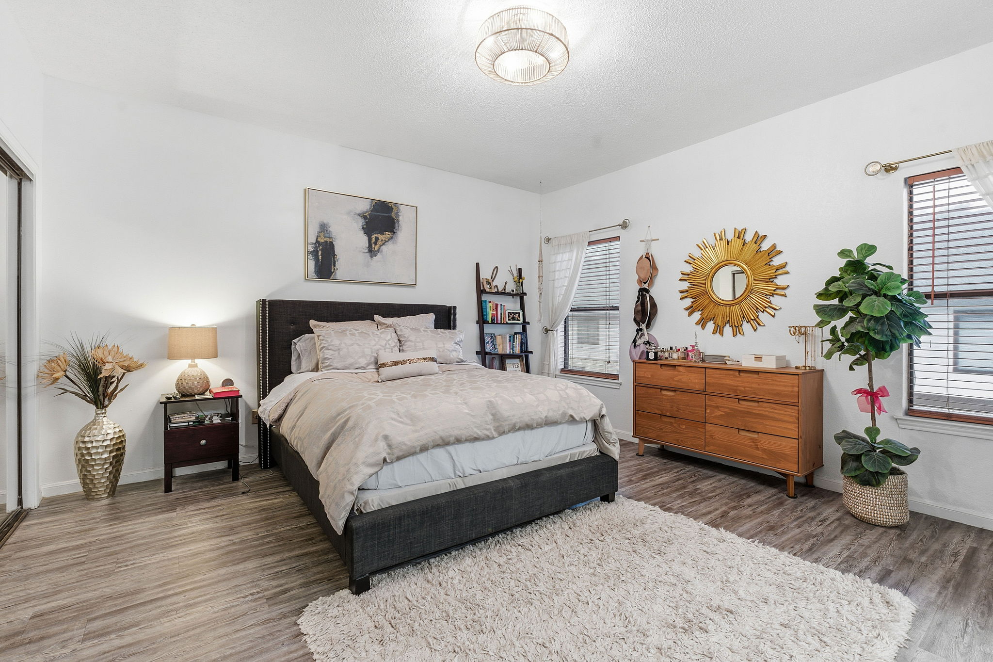 10819 Crown Colony Drive, Unit 33 Austin, TX 78747 - Photo 19 of 27 a bedroom with a bed potted plant on dresser and a wooden floor
