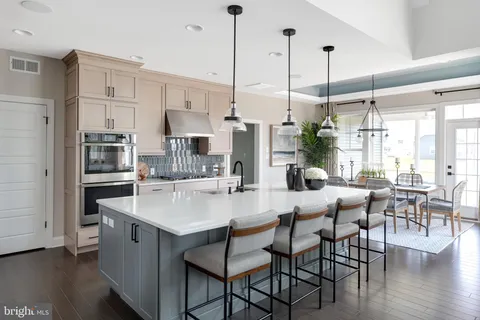 a kitchen with stainless steel appliances kitchen island granite countertop a table chairs stove and white cabinets