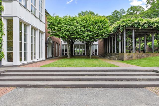 a view of a house with a small yard and large trees