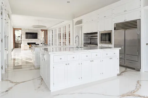 a large white kitchen with granite countertop a sink and dishwasher