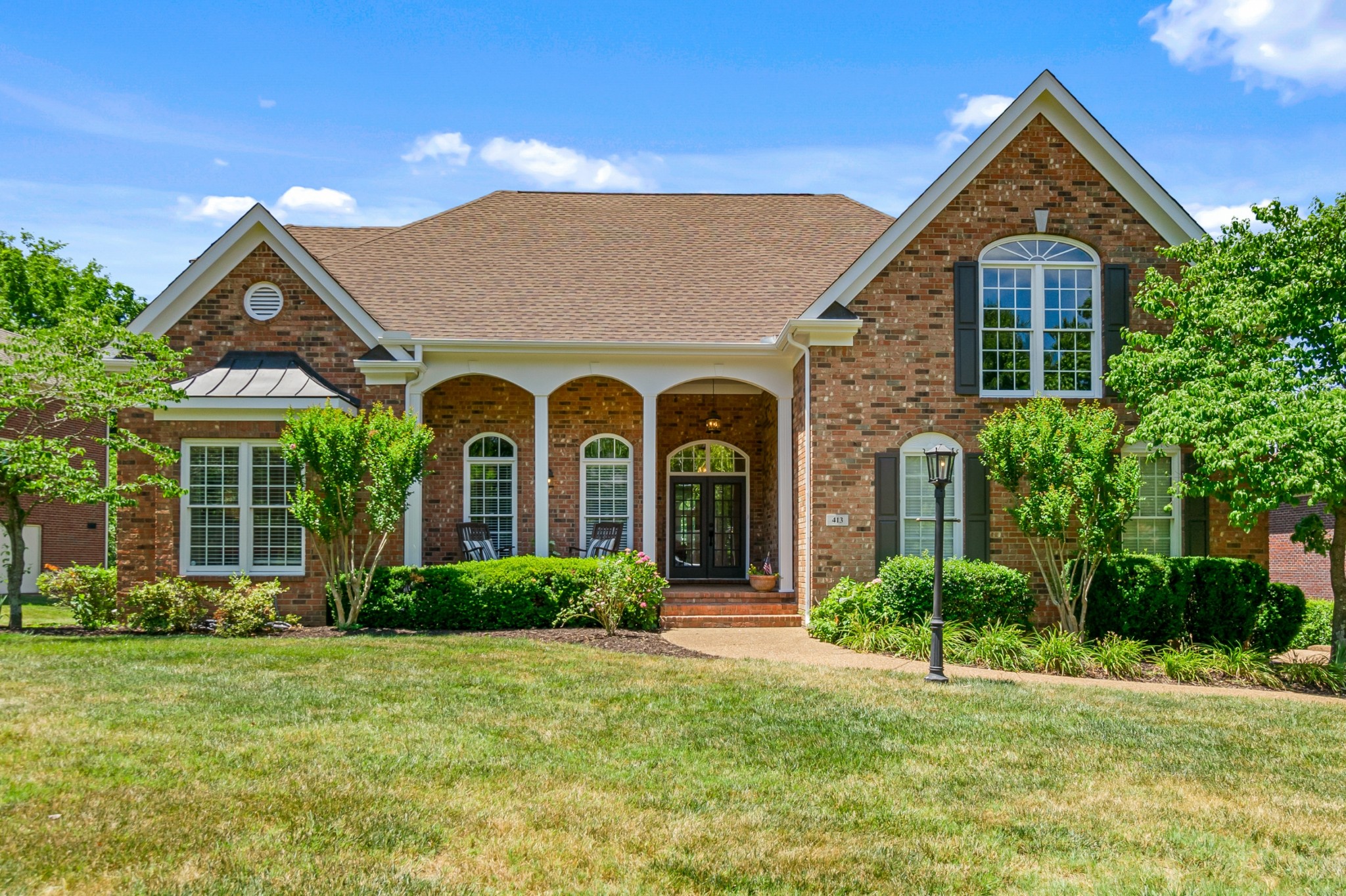 a front view of a house with a yard and potted plants