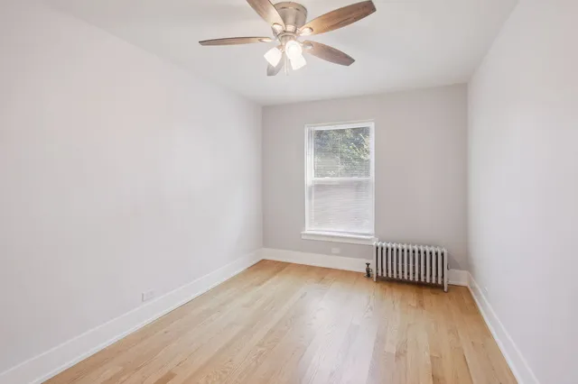 an empty room with wooden floor ceiling fan and windows