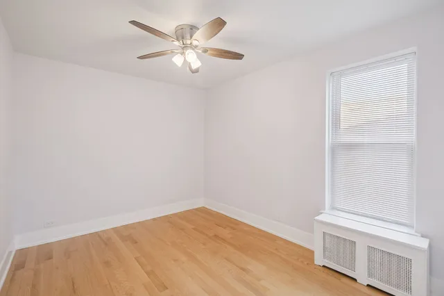 an empty room with a hardwood and ceiling fan