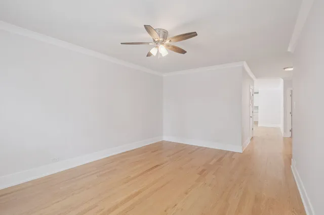 a view of a hallway with wooden floor and a ceiling fan