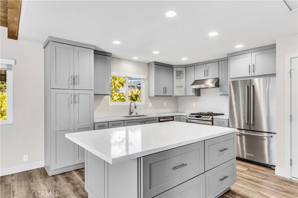 24502 Selva Road, Unit A2 Dana Point, CA 92629 - Photo 13 of 23 a kitchen with a refrigerator a sink dishwasher and white cabinets with wooden floor
