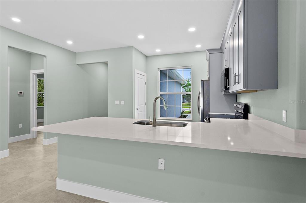 13 Karas Trail Palm Coast, FL 32164 - Photo 12 of 37 a kitchen with kitchen island a sink a stove and a refrigerator