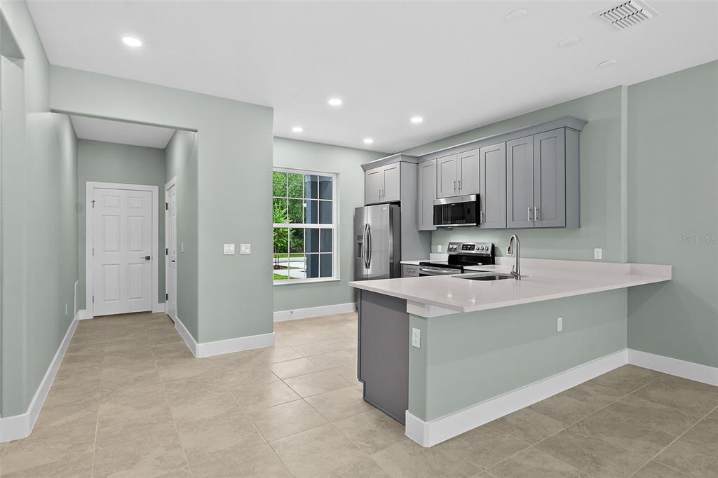 13 Karas Trail Palm Coast, FL 32164 - Photo 5 of 37 a kitchen with stainless steel appliances granite countertop a stove top oven a sink a refrigerator and a granite counter tops