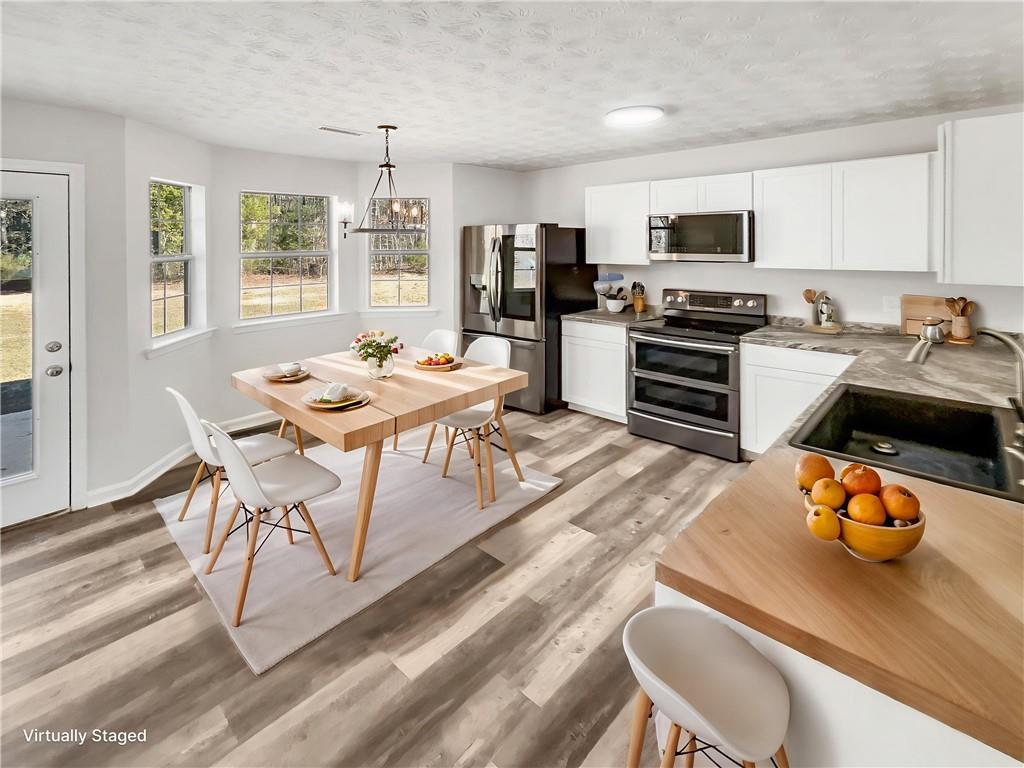 24 Chelsea Lane Grantville, GA 30220 - Photo 7 of 20 a kitchen with stainless steel appliances kitchen island granite countertop a sink dishwasher a stove a refrigerator with a dining table and chairs with wooden floor