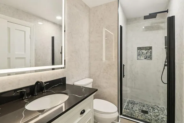 a bathroom with a granite countertop sink toilet and shower