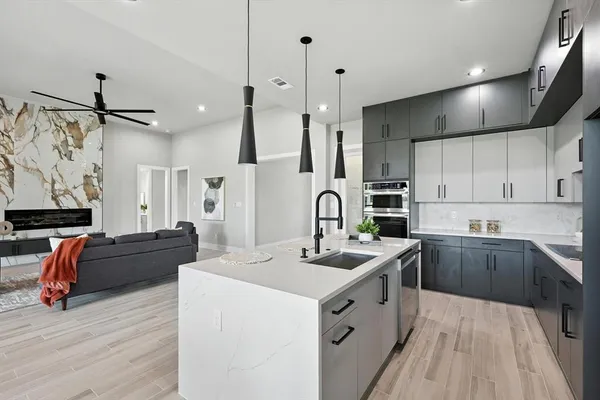 a large white kitchen with cabinets a sink and stainless steel appliances