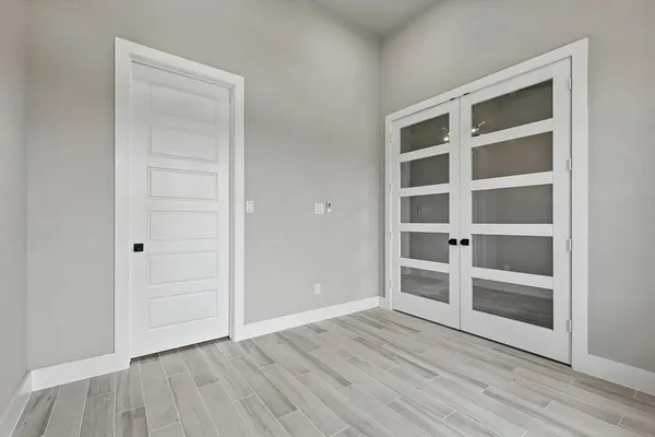 a view of an empty room with wooden floor and closet